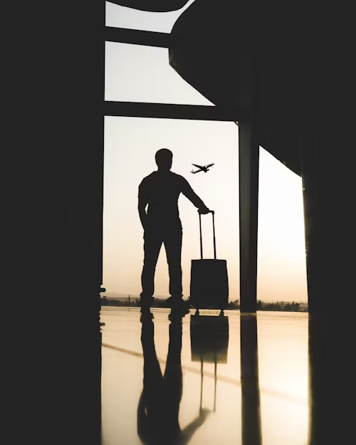 bărbat cu troler in mana așteptând la aeroport
