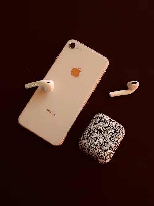 telefon de renume roz cu airpods lângă