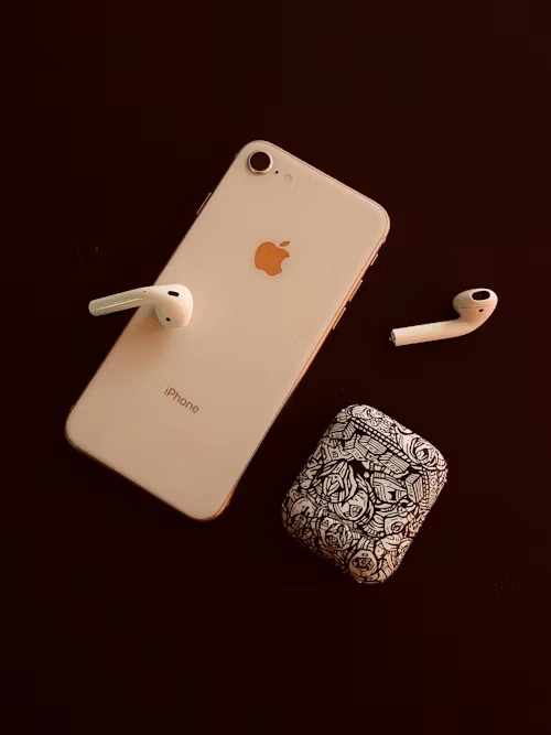 telefon de renume roz cu airpods lângă