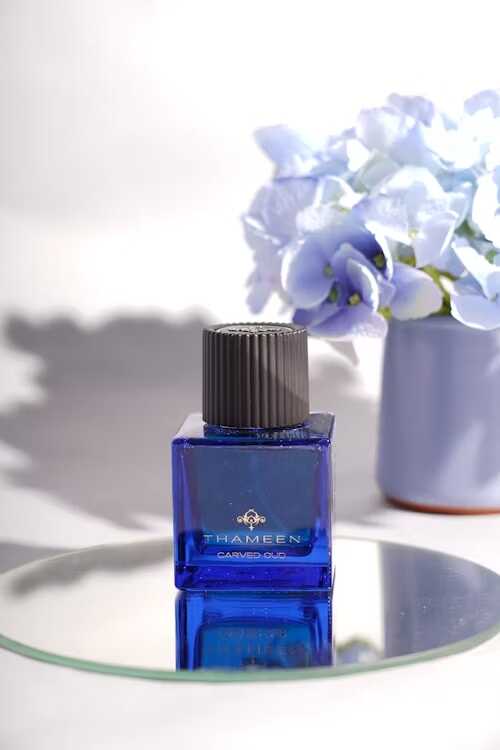 sticluța parfum albastra pe oglinda cu floare pe fundal