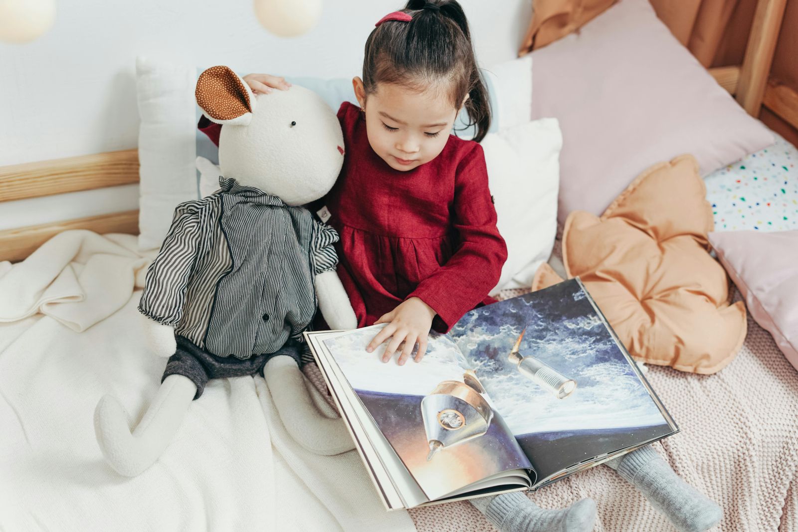 Un copil citește o carte cu un animal de pluș