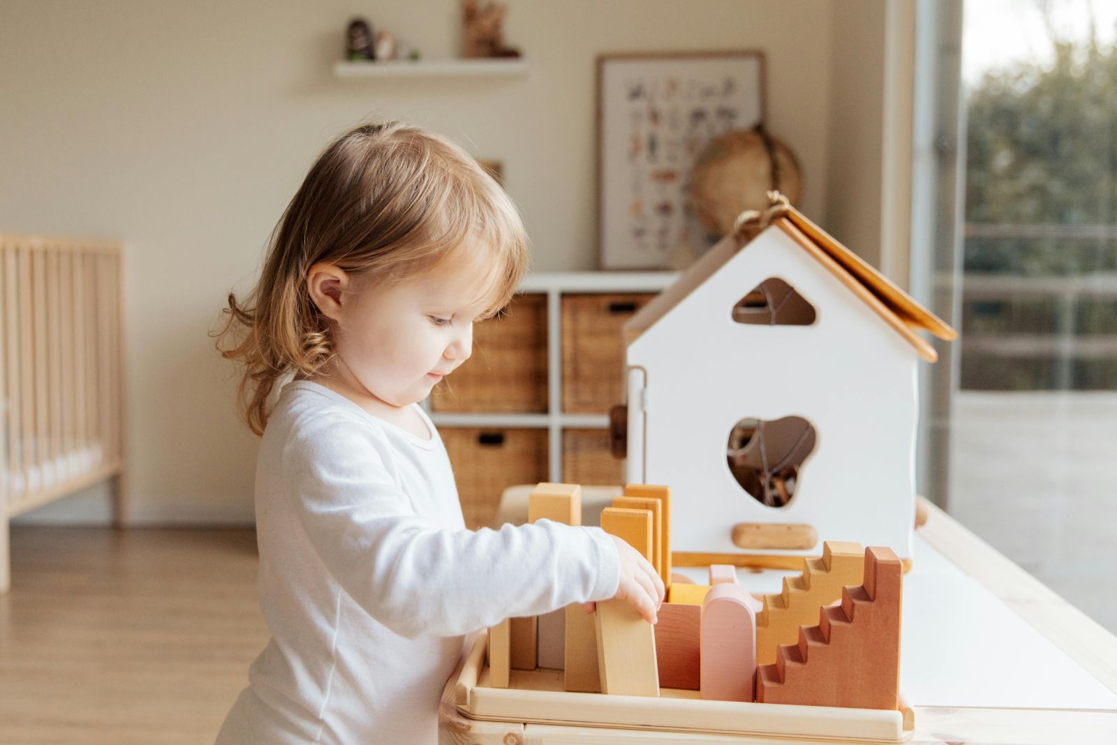 Un copil se joacă cu o casă de păpuși