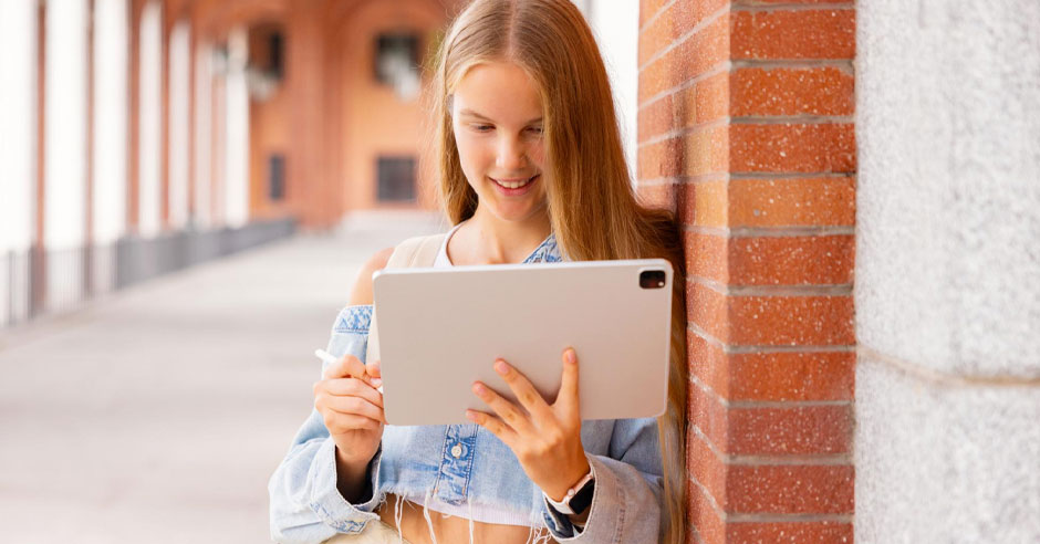 studentă pe culoarul școlii se uită pe tabletă